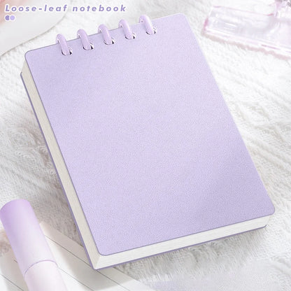 Cute Small notepad with light Pastel purple cover and lined pages on a white linen surface.