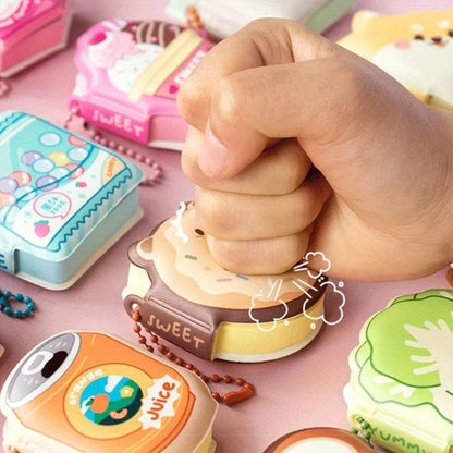 Hand pressing a small toy with colorful packaging on a pink surface